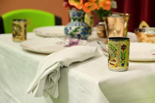 a table with a white table cloth and plates and vases at vaidehi homlee premium stay, 3kms from Shri Ram janmbhoomi, Ayodhya in Faizābād
