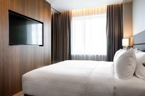 a hotel room with a white bed and a television at AC Hotel by Marriott Riga in Rīga