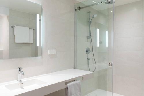 a bathroom with a shower and a sink and a mirror at AC Hotel by Marriott Riga in Rīga