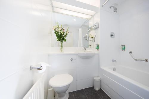 a white bathroom with a toilet and a sink at Dooley's Hotel in Waterford