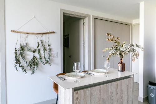 a kitchen with a table with wine glasses and greenery at Modern 1-Bedroom Apt in Núcleo Sabana Tower in San José