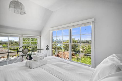 a bedroom with a large white bed and large windows at Charming House in Woolwich in Sydney