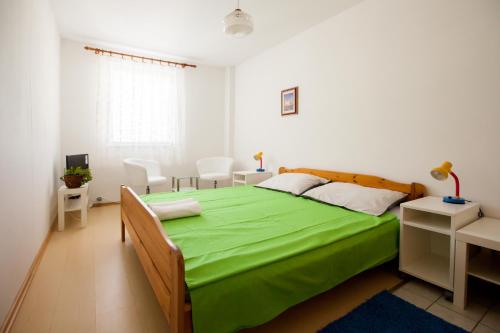1 dormitorio con cama verde, mesa y sillas en Friendly People's Guest House, en Zadar