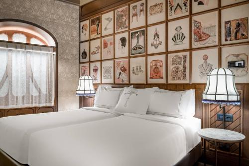 a bedroom with a large white bed and a wall of pictures at Palacio Santa Clara, Autograph Collection in Valencia
