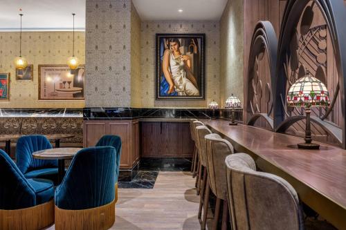 a bar with chairs and a painting of a woman at Palacio Santa Clara, Autograph Collection in Valencia
