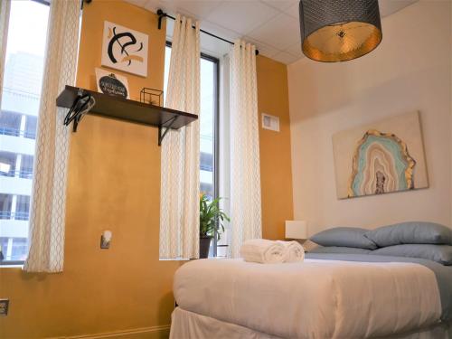 two beds in a room with yellow walls and a window at Stay Pittsburgh in Pittsburgh