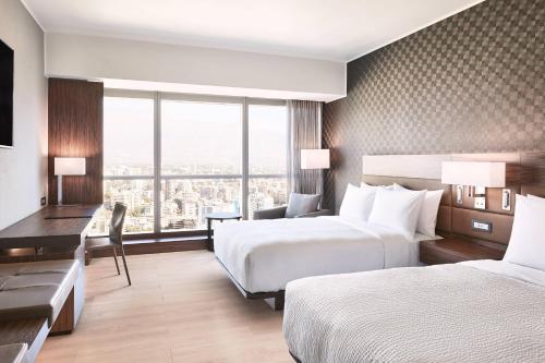 a hotel room with two beds and a desk at AC Hotel by Marriott Santiago Cenco Costanera in Santiago