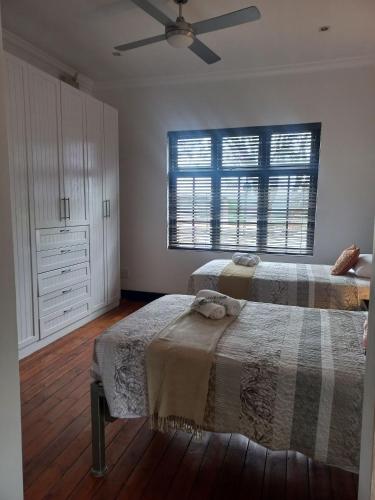 a bedroom with two beds and a ceiling fan at Jakess Place modern comfortable sunny 3-bedroom house in Kensington in Johannesburg