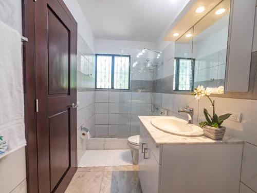 Un baño con lavabo, inodoro y espejo. en 7br Massive Villa In Sosa - 2mins From Nightlife, en Sosúa