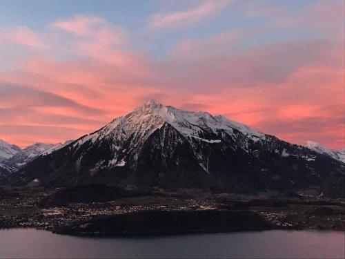 a snow covered mountain with a pink sky at Chalet with panoramic views of the mountains of the Oberland and Lake Thun in Sigriswil