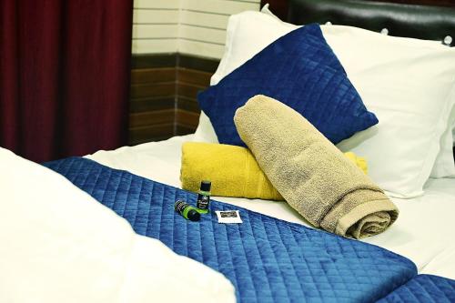 a bed with blue and white pillows and a towel at vaidehi homlee premium stay, 3kms from Shri Ram janmbhoomi, Ayodhya in Faizābād