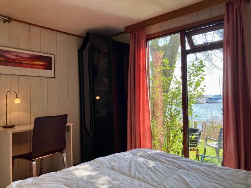 a bedroom with a bed and a large window at Tolles 2 Pers Haus König mit Hafenblick am Lauwersmeer in Anjum