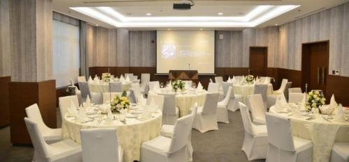 una sala de conferencias con mesas blancas y sillas blancas en The Envoy Hotel and Suites, en Abuja