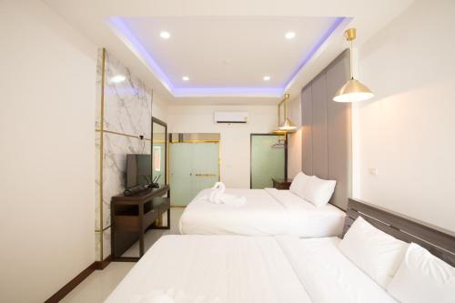 a hotel room with two beds and a television at Big Alice Pool Villa Pattaya in Ban Hui Yai Muk