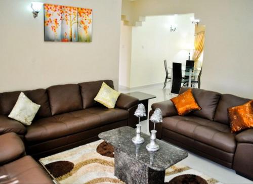 a living room with a brown couch and a table at Auris Court - 2 Bedroom Apartment in Jabi