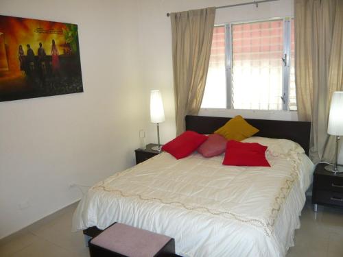 a bedroom with a bed with red and yellow pillows at Villa Los Almendros - 2 private pools tennis pickle ball in Baní
