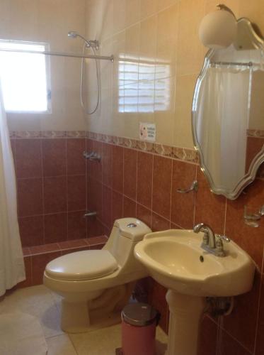 a bathroom with a toilet and a sink at Villa Los Almendros - 2 private pools tennis pickle ball in Baní
