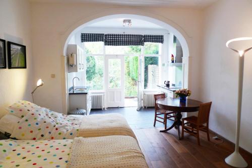 a bedroom with a bed and a table and a kitchen at Bed & Breakfast Walenburg in Rotterdam