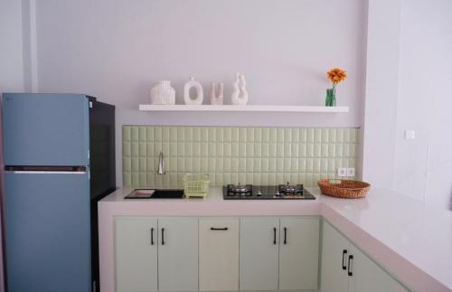 a kitchen with white cabinets and a blue refrigerator at Ponder Bali Canggu in Canggu