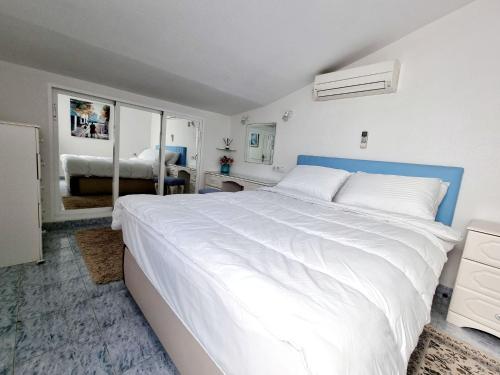 a bedroom with a large white bed and a mirror at Bungalow near the Salt Lakes of Torrevieja and La Mata and their beaches in La Mata