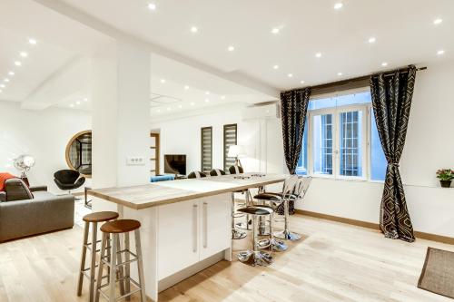 an open kitchen and living room with a bar and stools at Just Renovated 138m2 On The Seine in Paris