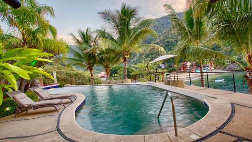 einen Pool mit 2 Stühlen und Palmen in der Unterkunft Family vacation home, 10 miles from downtown Pv romantic zone, ocean frontage in Puerto Vallarta