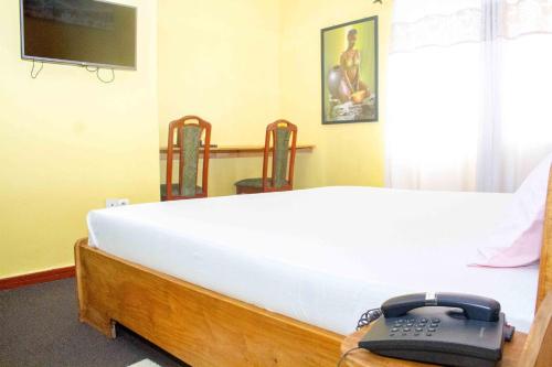 a bedroom with a bed with a phone on it at Hotel Bariba Playa relaxation experience in Cotonou