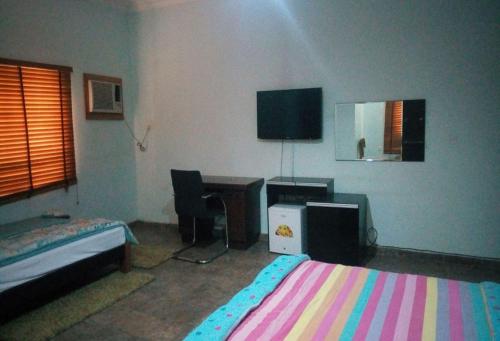 a bedroom with a bed and a desk and a tv at Wetland Hotels, Ibadan in Ibadan