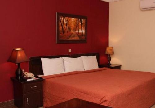 a red bedroom with a bed with a red wall at Agura Hotel - Standard King in Abuja