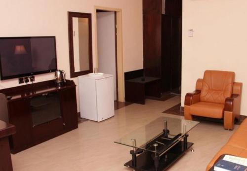 a living room with a tv and a couch and a chair at Agura Hotel - Standard King in Abuja