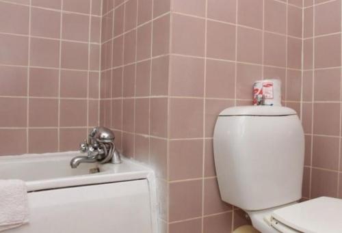 a pink bathroom with a toilet and a bath tub at Agura Hotel - Standard King in Abuja