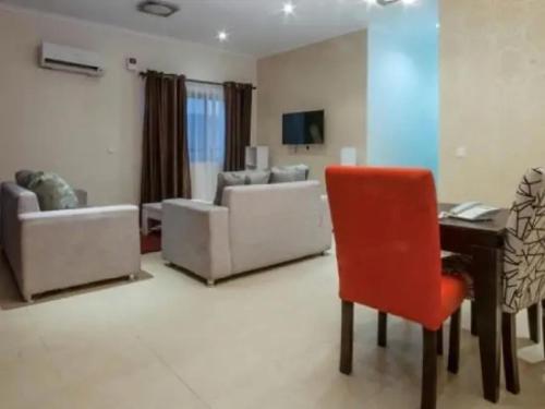 a living room with a red chair and a piano at Goosepen 3 Bedrooms Apartment in Lagos