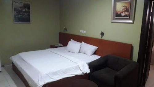 a bedroom with a white bed and a chair at Divine Fountain Hotel - Deluxe in Lagos