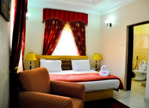 a bedroom with a bed with a window and two chairs at Auris Court - Economy in Jabi