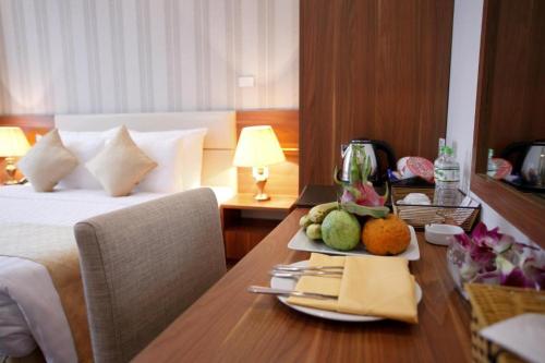 a hotel room with a bed and a table with a plate of fruit at The Embassy Hotel Hanoi in Hanoi