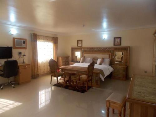 a bedroom with a bed and a table and chairs at Ayalla Hotels Suites-abuja Royal Suite in Port Harcourt