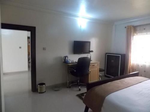 a bedroom with a bed and a desk with a television at Ayalla Hotels Suites-abuja Royal Suite in Port Harcourt