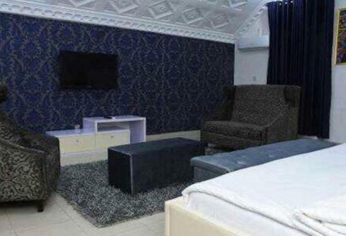 a bedroom with a bed and a chair and a tv at Ambience Hotel Magodo - Deluxe in Lagos