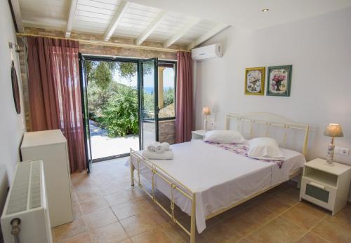 a bedroom with a bed and a large window at Villa Angelo ΙΙ in Paleokastritsa