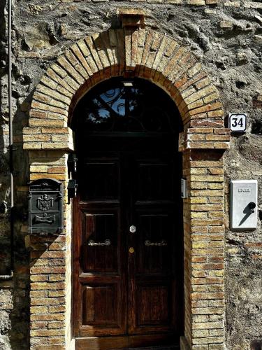 una puerta de madera en una pared de ladrillo con un arco en Appartamento Appia Castel Viscardo, en Castel Viscardo