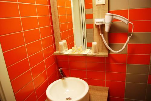 a bathroom with orange tiles and a sink at The Originals City, Hôtel Clermont-Ferrand Sud Aubière in Aubière