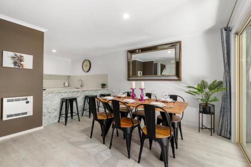 a dining room with a table and chairs and a mirror at Elvis - The Great Seaside Escape - Luxury Stay in Coffs Harbour