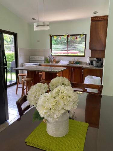 a vase with white flowers on a table in a kitchen at Holiday Beach House In Punta Leona - wprivate Pool in Punta Leona