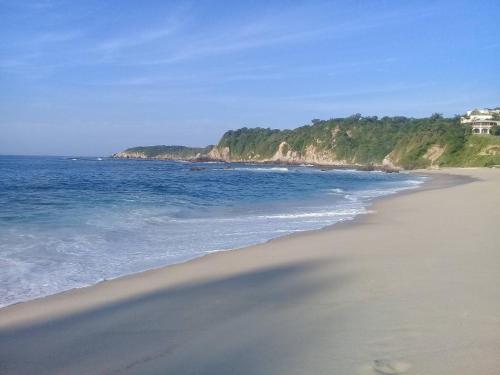 a view of a beach with a house in the distance at Departamento Completo, Playa Paradisiaca, in Cuatunalco