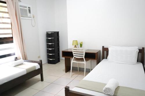 a bedroom with a bed and a desk with a chair at Natos Residences - St Francis in Bacolod