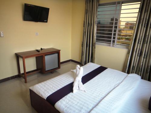 a bedroom with a bed and a tv and a window at Khemra I Guesthouse in Kampot