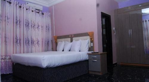 a hotel room with a bed with white pillows at Royal Park Hotel Suite - Standard in Asaba