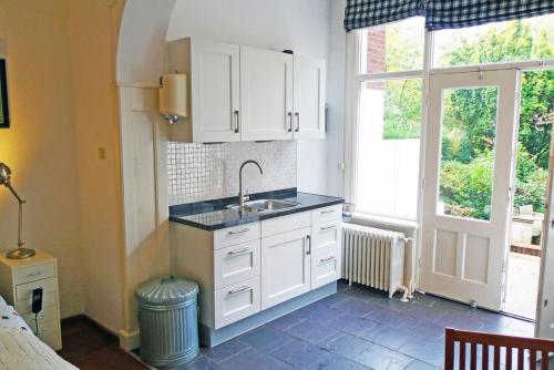 a kitchen with white cabinets and a sink and a window at Bed & Breakfast Walenburg in Rotterdam