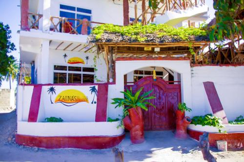 a building with a red door with plants on it at Room Ally at the beach for 2 - 3 guests in Nungwi