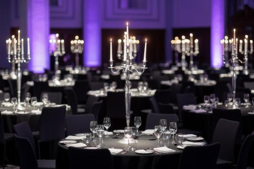 a large banquet hall with tables with glasses and chandeliers at Kimpton Clocktower by IHG in Manchester